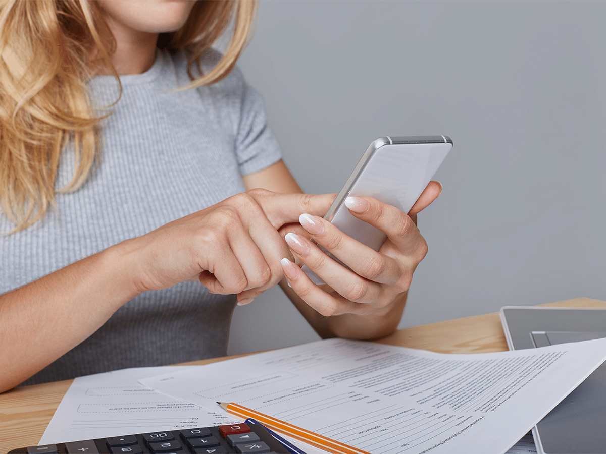 Mujer haciendo registro de sus gastos mensuales a través del celular